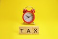 tax word from wooden letters and red alarm clock Royalty Free Stock Photo