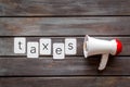 Taxes announcement with megaphone and text on wooden background top view