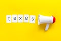 Taxes announcement with megaphone and text on yellow background top view