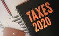 Taxes 2020 on copybook cover, financial report, pen and wallet. Business concept for fees and taxes optimization, reduce personal