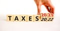 2023 taxes new year symbol. Businessman turns a wooden cube and changes words Taxes 2022 to Taxes 2023. Beautiful white table