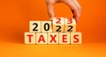 2023 taxes new year symbol. Businessman turns a wooden cube and changes words Taxes 2022 to Taxes 2023. Beautiful orange table