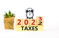 2023 taxes new year symbol. Turned wooden cube and changes words Taxes 2022 to Taxes 2023. Black alarm clock. Beautiful white