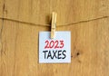 2023 taxes new year symbol. White paper with words 2023 taxes, clip on wooden clothespin. Beautiful wooden background. Business