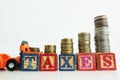 Taxes word on wooden cubes with scale of money above pushed by orange forklift