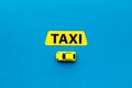 Taxi concept. Yellow service sign text taxi near car toy on blue background top view space for text