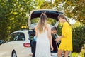 Taxi driver putting luggage of women in trunk of car