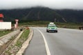 A taxi drives past a petrol station and cloud-covered mountains in south-west China