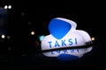 Taxi light sign or cab sign in blue and white color on the car roof at the street in the dark night