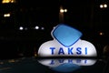 Taxi light sign or cab sign in blue and white color on the car roof at the street in the dark night