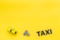 Taxi operator concept. Chip service. Sign taxi ner car toy and coins on yellow background top view copy space