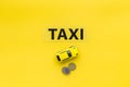 Taxi operator concept. Chip service. Sign taxi ner car toy and coins on yellow background top view copy space