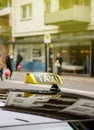 Taxi sign waiting for customers in city with defocused pedestrians