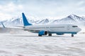 Taxiing of a passenger jetliner on the airport apron in a snow blizzard on the background of high scenic snow capped mountains