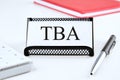 TBA the word on the business card standing on a stand next to a notepad, calculator and pen Royalty Free Stock Photo