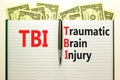 TBI traumatic brain injury symbol. Concept words TBI traumatic brain injury on white note on a beautiful background from dollar