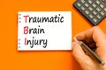 TBI traumatic brain injury symbol. Concept words TBI traumatic brain injury on white note on a beautiful orange background. Doctor
