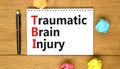 TBI traumatic brain injury symbol. Concept words TBI traumatic brain injury on white note on a beautiful wooden table wooden