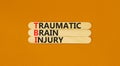 TBI traumatic brain injury symbol. Concept words TBI traumatic brain injury on wooden stick on a beautiful orange table orange