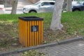 Wooden brown urn with a sign in the park.