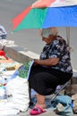 Old woman under umbrella in summer sun sells cloth Dry Bridge Market Tbilisi Georgia