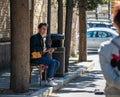 A young man looks at a passing girl and plays a Georgian string instrument in Tbilisi city in Georgia