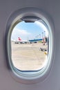 Airplane porthole window view at planes in airport Royalty Free Stock Photo