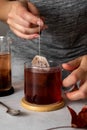 Tea bag in glass cup of tea. Female hand with bag of black tea. Hot drink, lifestyle photo Royalty Free Stock Photo