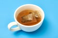 Tea bag in a white cup on a blue background. Making delicious herbal tea Royalty Free Stock Photo