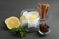 Tea bags, anise stars, cinnamon sticks, mint and lemon on grey wooden table