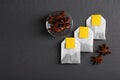 Tea bags and anise stars on grey wooden table, flat lay. Space for text