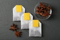 Tea bags and anise stars on grey wooden table, flat lay