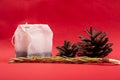 Tea bags close-up with pine cones and a sprig of spruce on a red background. forest flavored tea Royalty Free Stock Photo