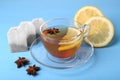 Tea bags, cup of hot drink, anise stars and lemon on light blue wooden table