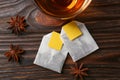 Tea bags, cup of hot drink and anise stars on wooden table, flat lay