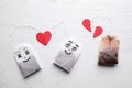 Tea bags with drawn faces on white background, flat lay. Concept of jealousy Royalty Free Stock Photo