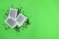 Tea bags with scattered dry leaves on color background, top view. Royalty Free Stock Photo