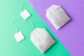 Tea bags with white labels on a pastel green and purple background. Royalty Free Stock Photo