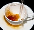 Tea being poured into a saucer with splashes on a black background Royalty Free Stock Photo