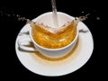 Tea being poured into a saucer with splashes on a black background Royalty Free Stock Photo