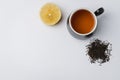 tea in a black mug, lemon segment and dried tea isolated on white background. Top view and copyspace
