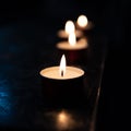 Tea candles in a church resting on a dark surface reflect their light