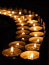 Tea candles in a row burning on black background Royalty Free Stock Photo