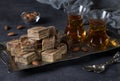 Tea ceremony with Uzbek sweet milk halva with almonds and cocoa on dark background.