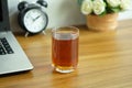 Tea in a clear glass on a wooden office desk with laptop computer, Tea afternoon break