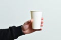 Tea or coffee paper cup in man hand isolated on blue background. Male hand holding the paper cup. Mockup of men hand holding a Royalty Free Stock Photo