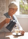 Tea comfort in a cup. A content senior woman pouring tea while sitting at home. Royalty Free Stock Photo