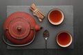 Tea composition with ceramic tea cups and red iron teapot on dark stone background Royalty Free Stock Photo