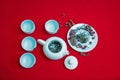 Tea composition with Chinese traditional tea cups and teapot on the background of red velvet fabric.