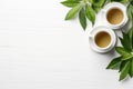 Tea Concept: Two White Cups of Tea and Teapot Surrounded with Green Tea Leaves AI Generated Royalty Free Stock Photo